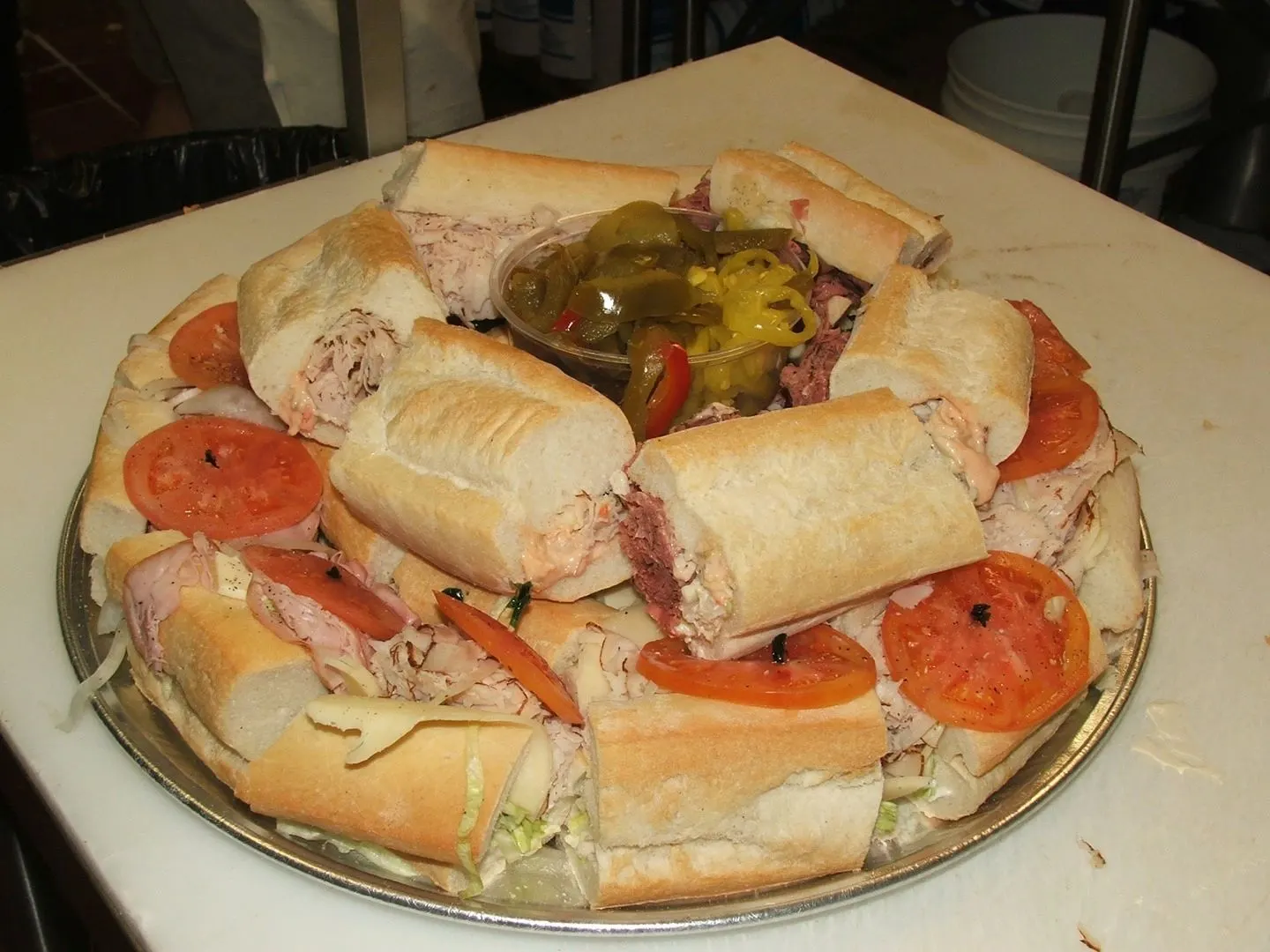 Italian subs stacked with deli meat, cheese, tomatoes and peppers on a party platter